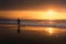 Lonely person walking on beach at sunset