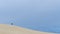 Lonely person walks on the sand dunes of the Little Sahara on Kangaroo Island, Southern Australia against the blue sky