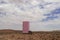 A lonely pink refrigerator stands in the Namib desert against the backdrop of a cloudy sky
