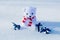 Lonely polar bear toy with a striped scarf and a gifts in the snow