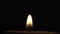 A lonely and quiet candle flame in complete darkness