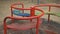 Lonely red empty deserted swing in an old abandoned amusement park. Swinging seat moving back and forth. Carousel