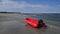 Lonely red rubber dinghy with outboard motor at low tide on the Baltic Sea