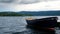 Lonely rowboat tied to floating lake dock bobs gently in waves under cloudy skies. Near Hurdal, Akershus, Norway