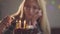 Lonely sad girl sitting in front of little cake lighting candles. Unhappy woman has birthday party. Concept of