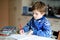 Lonely school kid boy at home making homework. Little child writing with colorful pencils, indoors. Elementary school