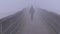 Lonely schoolboy walking in winter fog on bridge