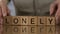 Lonely, senior man making word of wooden cubes, people in retirement home