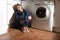 Lonely and sick woman sitting on kitchen floor in stress depression and sadness