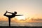 Lonely silhouette of woman practicing yoga on the beach at sunset