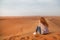 Lonely sitting redhead woman in evening desert meditating outdoors