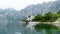 Lonely small boat in a fisherman village in the bay of Kotor. Lake surrounded by grey big mountains and green brushes. Landscape