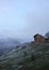 Lonely stone house on the hill on the background of snowy mountains, overcast, dark