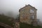 Lonely stone house on the hill in fog, side view
