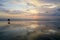 Lonely surfer walking along empty Kuta beach with sunset sky