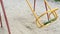 Lonely swing like symbol loneliness and boring. Solitariness empty playground swing on sand. Extreem slow motion colour.