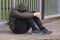 Lonely teenager sitting alone outside a metal fence with iron bars. Loneliness and bullying concep