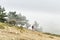 Lonely tourist looks at huge fog cloud standing on mountain