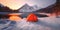 lonely tourist orange tent on a snow near Mountain Lake