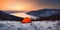 lonely tourist orange tent on a snow near Mountain Lake