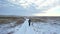 A lonely tourist walks along a snow-covered road through an endless snow field. The concept of travel in extreme