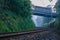 Lonely train tracks disappearing under a bridge and into a foggy morning landscape