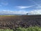 A lonely tree on the horizon stands at the junction of the blue sky with clouds and plowed lumps of wet soil after rain. Country