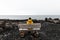 Lonely unrecognized traveler man in yellow rain jacket  is relaxing at nice view of sea with wooden bench in Iceland