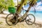 Lonely vintage bicycle on the tropical  sandy beach by a palm tree with sky and calm sea at background