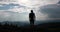 Lonely walk in the mountains. Look from behind at a man with backpack standing before beautiful mountain landscape and