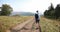 Lonely walk in the mountains. Man walks along the road on a hill with great landscape before him and looks over his