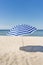 Lonely white and blue strip umbrella on the beach.
