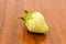 Lonely white unripe strawberry lying on the table in the sun