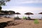 Lonely wicker sun umbrella at beach by sea. Natural bamboo sunshades, summer umbrella parasol, deck chairs, table, sun bed.