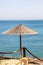 Lonely wicker sun umbrella at mediterranean beach by sea. Natural bamboo sunshades and summer umbrella parasol on ocean beach.