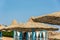 Lonely wicker sun umbrella at mediterranean beach by sea. Natural bamboo sunshades and summer umbrella parasol on ocean beach.