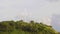 A lonely wind power generator standing on a mountain in a thicket of trees against a background of blue sky and beautiful cumulus