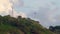 A lonely wind power generator standing on a mountain in a thicket of trees against a background of blue sky and beautiful cumulus