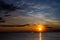 Lonely Wind surfer setting sail towards the dramatic and magnificent scenic sunset at the coast of the mediterranean sea in