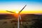 Lonely windmill turbine peacefully rotating blades through the wind in the beautiful sunset sky