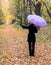 Lonely woman with bright umbrella in autumn forest