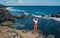 Lonely woman dressed light summer clothes enjoying Indian ocean view with strong surf on cliff at Gris Gris viewpoint extreme