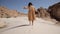 lonely woman legs go along the desert barefoot on the sand leaving footprints close-up. Girl in yellow dress walking