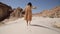 lonely woman legs go along the desert barefoot on the sand leaving footprints close-up. Girl in yellow dress walking