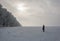 Lonely woman looking at the sun at the field with row of frosty oaks in winter