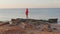 Lonely woman in the red t-shirt is standing on stones at the shore She waiting for sunrise