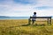 Lonely woman sitting on a bench in front of the ocean on a sunny summer day