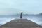 lonely woman standing on a pier by the sea gets carried away by emotions in a blue surreal atmosphere