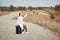 A lonely woman with a suitcase is walking on an empty road without a cellular connection, trying to catch a phone signal