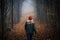 Lonely woman walking on footpath in dark foggy mystery forest